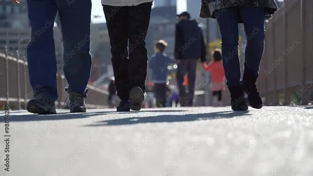 Pedestrians walk on a busy bridge walkway on a sunny, autumn day. Pedestrians walk on a busy bridge walkway on a sunny, autumn day.