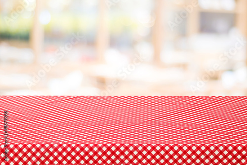 Empty table with red check table cloth over blurred cafe photo