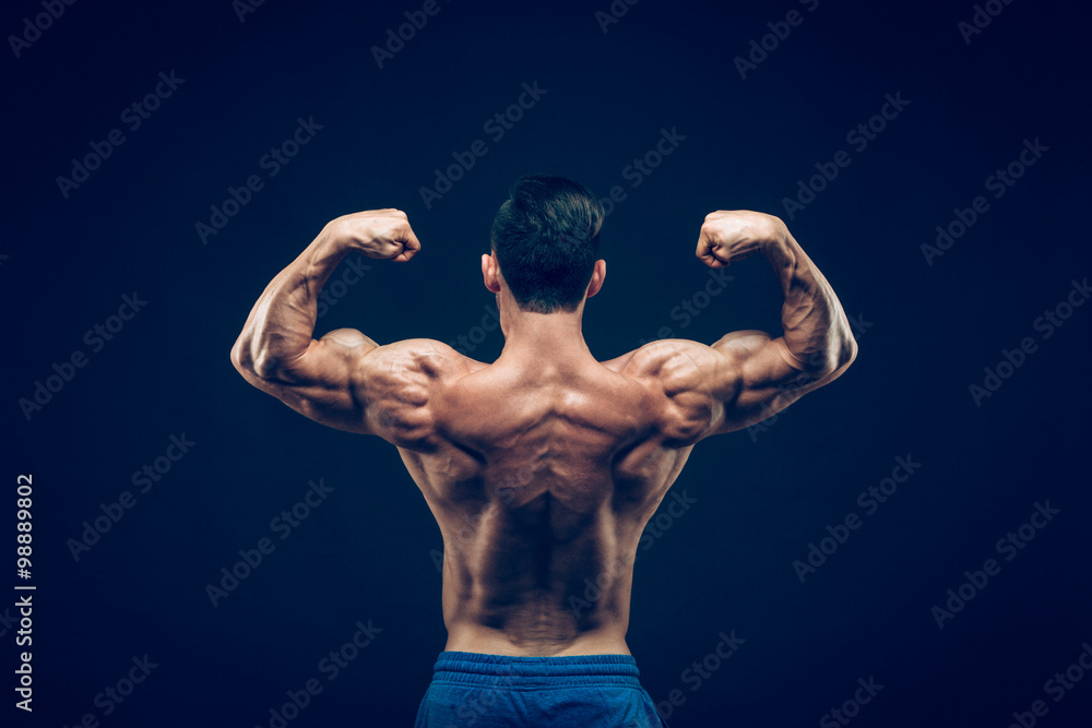 Fototapeta premium Muscular man posing in dark studio on black background.