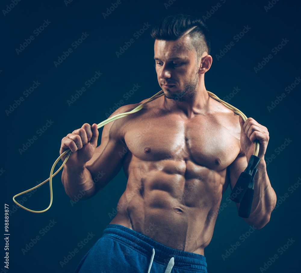 Muscular man skipping rope. Portrait of muscular young men exercising with jumping rope on black background