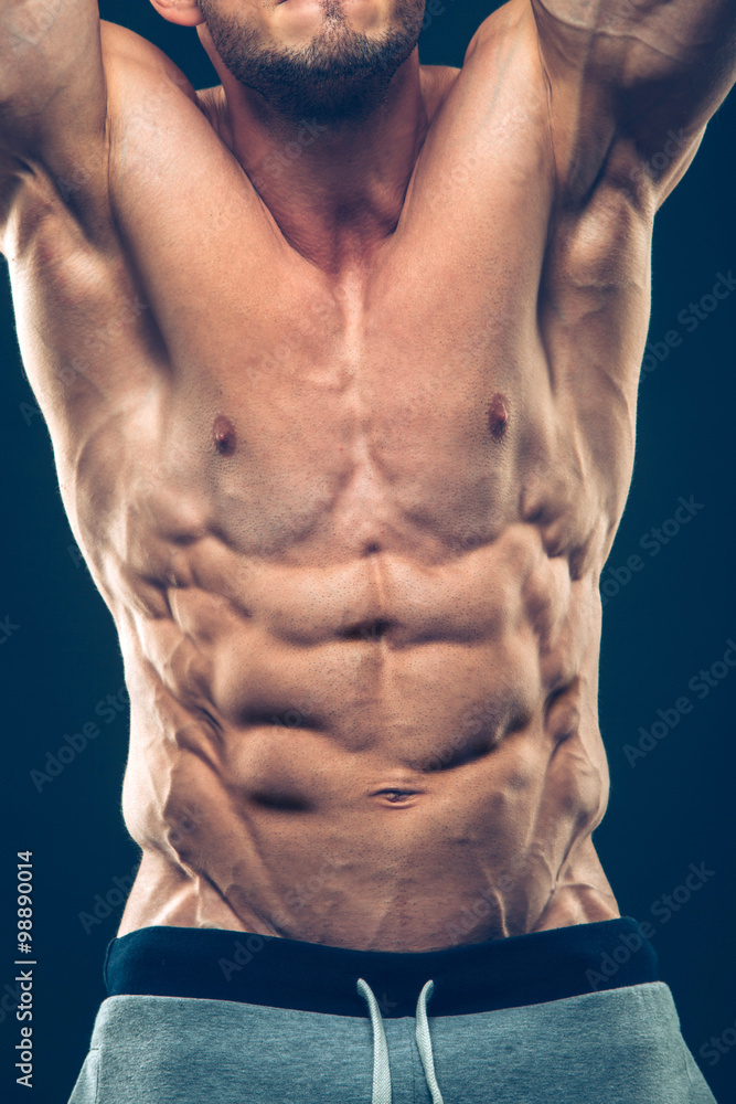 Fototapeta premium Strong Athletic Man Fitness Model Torso showing six pack abs. isolated on black background with copyspace