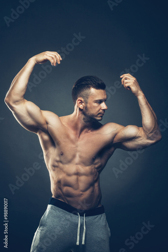 Strong Athletic Man Fitness Model Torso showing six pack abs. isolated on black background with copyspace