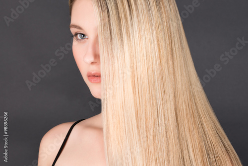 Beautiful young blonde woman with long straight hair on a dark background