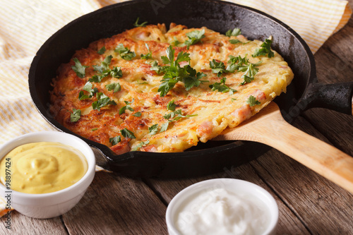 Potato rosti with herbs close-up in a pan on the table. Horizontal
