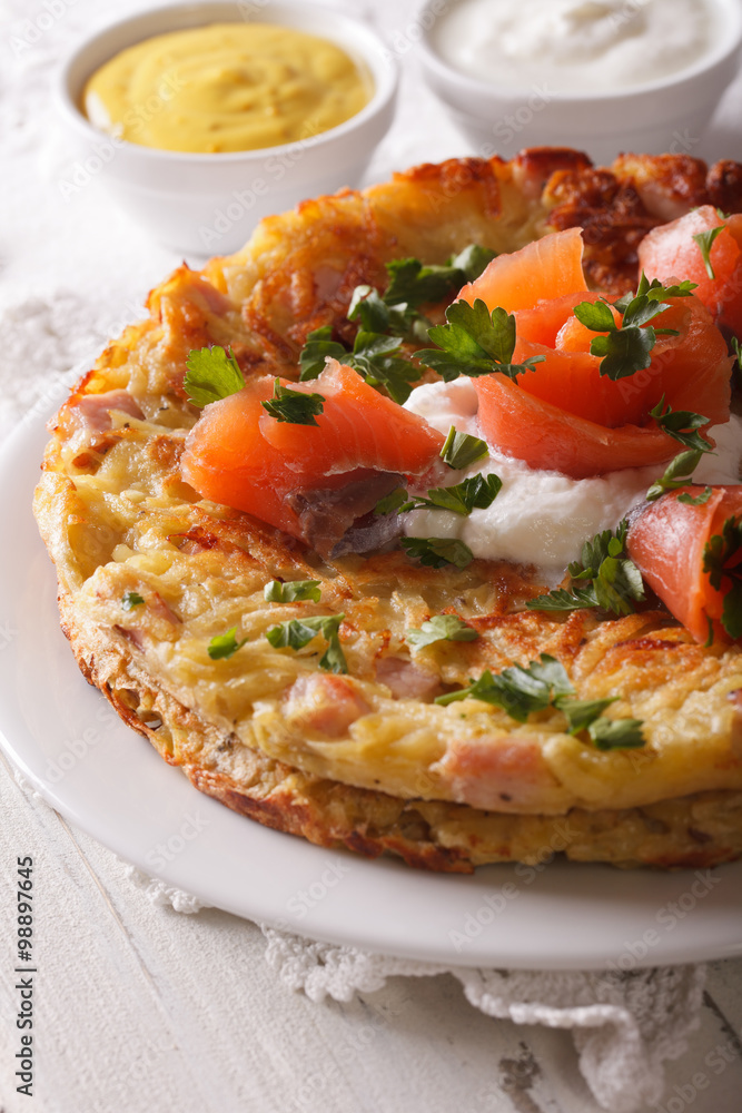 Potato rosti with smoked salmon close-up on a plate. vertical Potato rosti with smoked salmon close-up on a plate. vertical