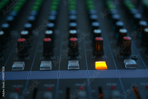 Close up of the rows of knobs and sliders on an analogue mixing