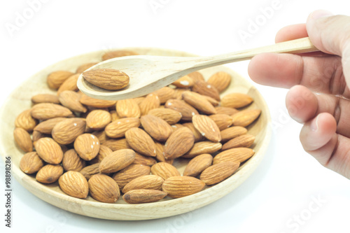 Hand on spoon of almond isolated on white background