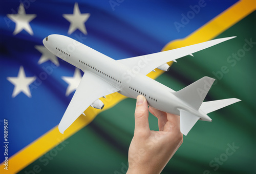 Airplane in hand with flag on background - Solomon Islands