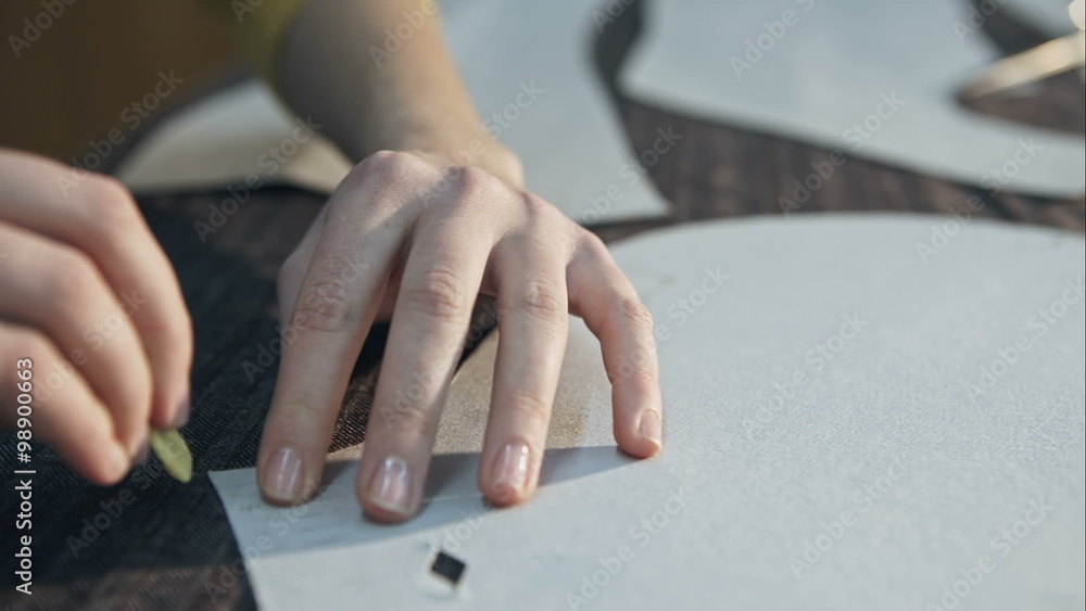 Close up of the hands of a seamstress marking a fabric with a chalk at her sewing atelier Close up of the hands of a seamstress marking a fabric with a chalk at her sewing atelier
