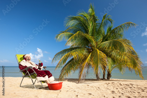 Santa Claus sitting in deck chair on beach