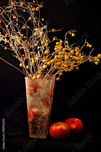 Red apples and vase of flowers on black background