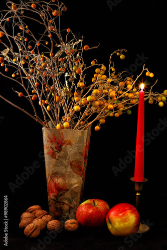 Apples ,walnuts and vase of flowers on black background