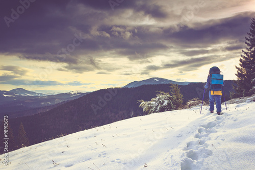 Young girl backpacker hiking in the winter mountains.
