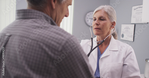 Doctor listening to patient's heart rate with stethoscope