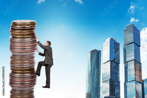 Schilderij op canvas Businessman climbing up a huge stack of coins