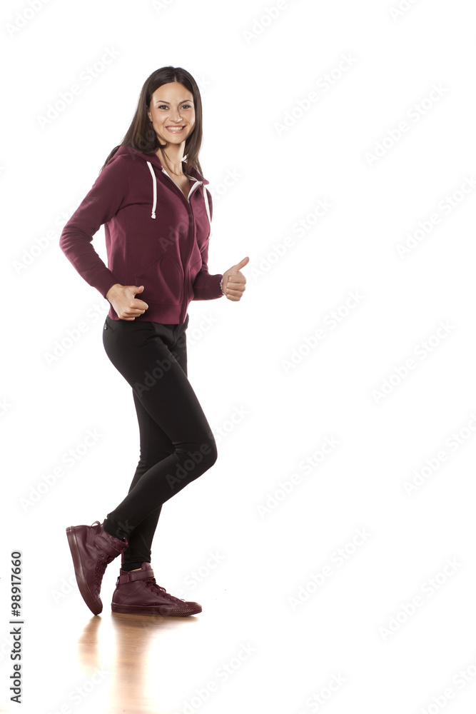 happy young woman in a track suit and pants showing thumbs up happy young woman in a track suit and pants showing thumbs up