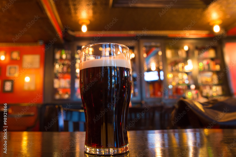 Glass of dark beer in pub setting
