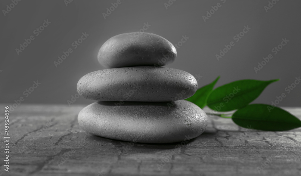 Pile of pebbles with leaf on the table against grey background Pile of pebbles with leaf on the table against grey background