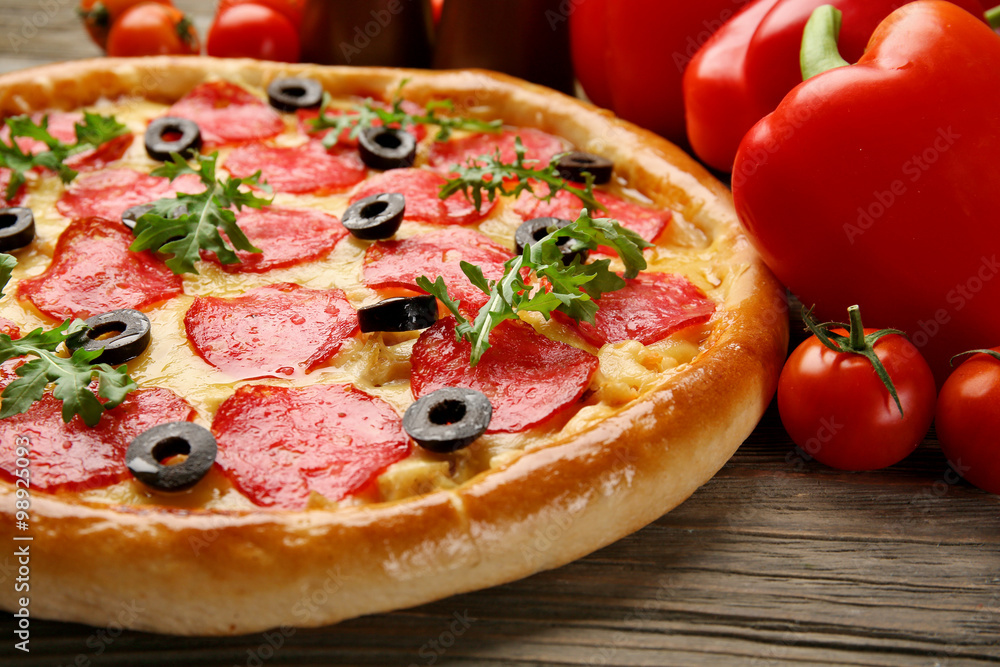 Tasty pizza with salami and red vegetables on wooden background, close up Tasty pizza with salami and red vegetables on wooden background, close up