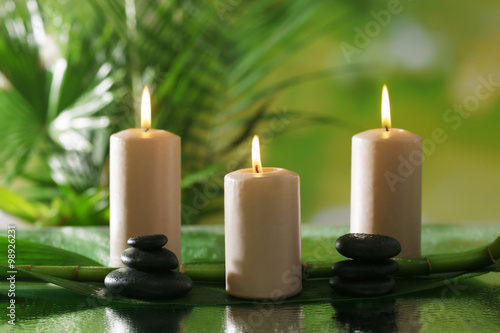 Spa composition of candles, stones and bamboo on blurred background