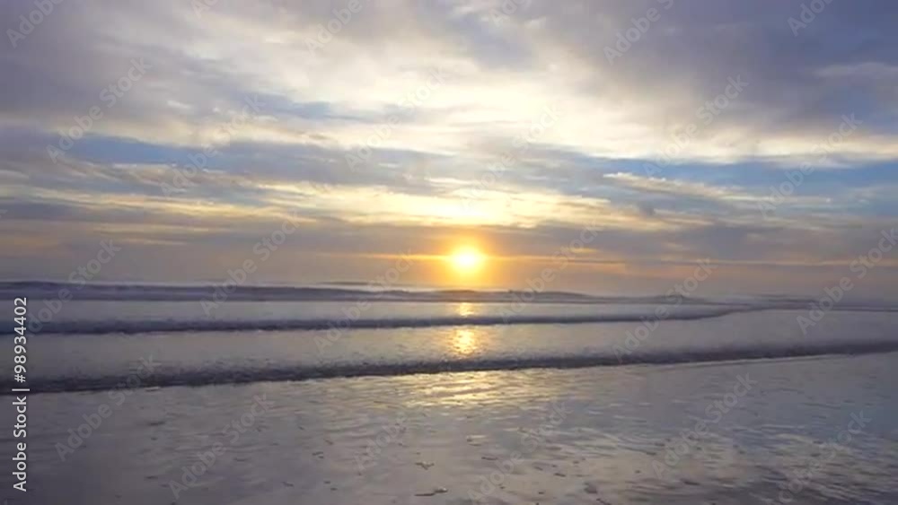 Waves roll into shore as the sun rises over the ocean. Sun flare added in post. Waves roll into shore as the sun rises over the ocean. Sun flare added in post.
