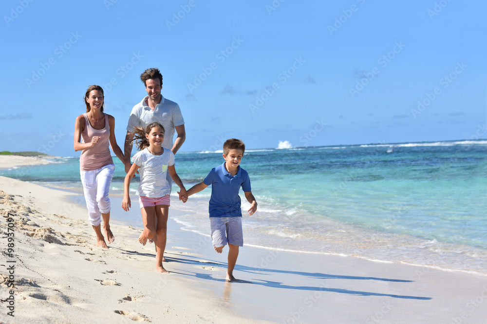Family of four running on a sandy caribbean beach