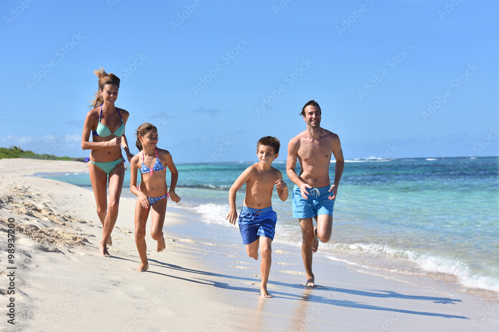 Family runnning on a sandy beach in Caribbean island