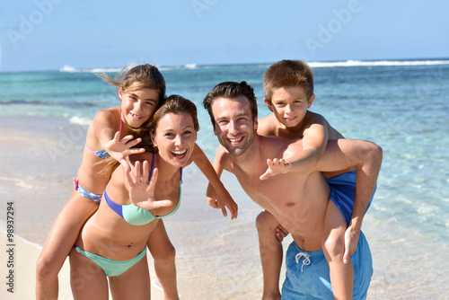 Portrait of cheerful family at the beach, piggyback ride