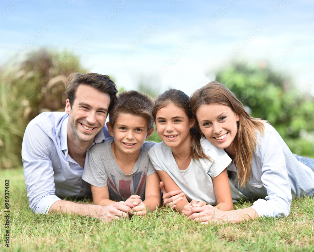 Portrait of happy family laying down in grass Portrait of happy family laying down in grass