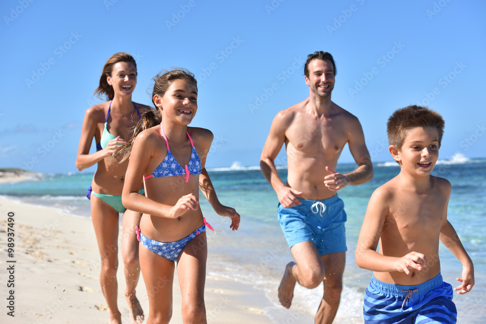 Family runnning on a sandy beach in Caribbean island Family runnning on a sandy beach in Caribbean island