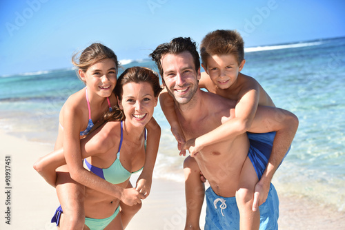 Portrait of cheerful family at the beach, piggyback ride