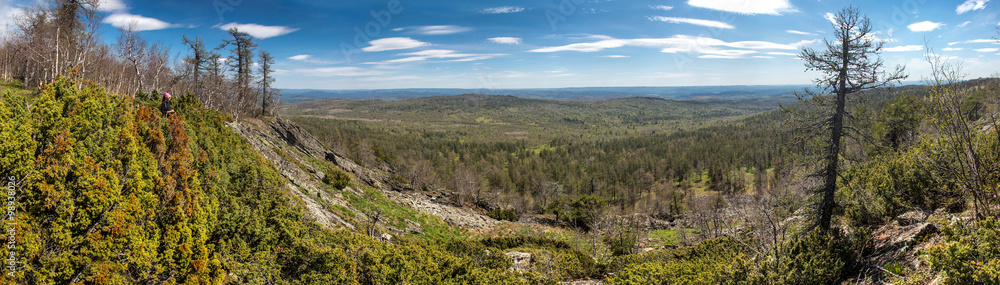 Panoramic view of woman hiker on a rocky mountain. Spring hike t