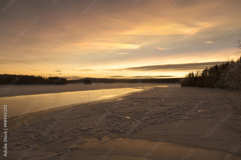 Obraz premium A partly frozen river and a sunset with snow
