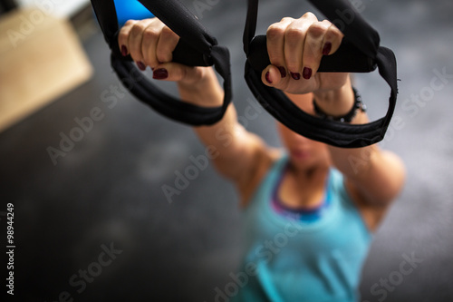Fotografie Young female at the gym working on her abs on trx