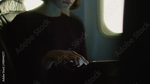 Young woman in close-up is using a tablet inside an airplane next to a window. Shot on RED Cinema Camera.