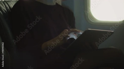 Young woman in close-up is using a tablet inside an airplane next to a window. Shot on RED Cinema Camera.