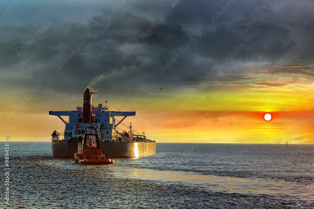 Tanker ship on sea in the rays of the setting sun.