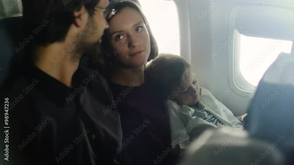 Romantic moment with a family with child on board of a plane next to a window. Romantic moment with a family with child on board of a plane next to a window.