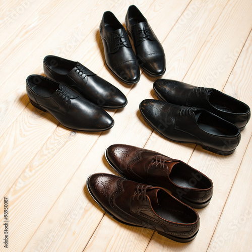 several pairs of men's leather shoes on wooden background