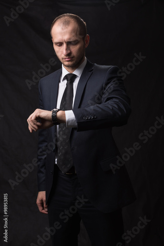 Portrait of young man in tie looking at his watch