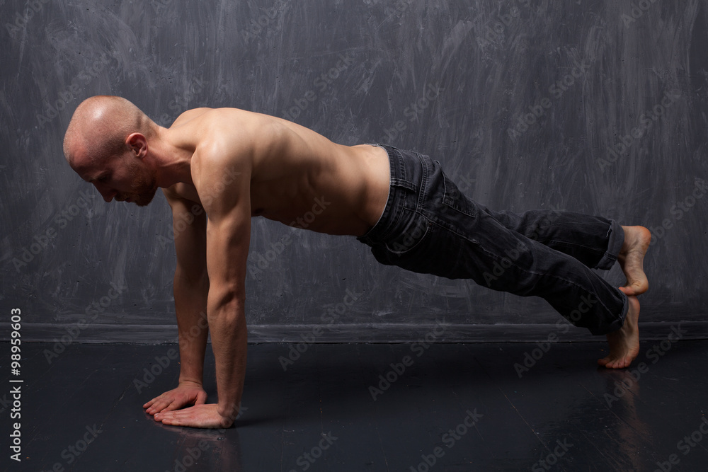 Young strong man with a naked torso doing push-ups Young strong man with a naked torso doing push-ups