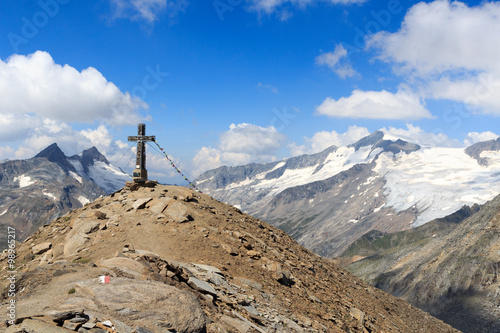 Summit cross and prayer flag on mountain Kreuzspitze with glacier panorama and Großvenediger in the Hohe Tauern Alps, Austria © johannes86