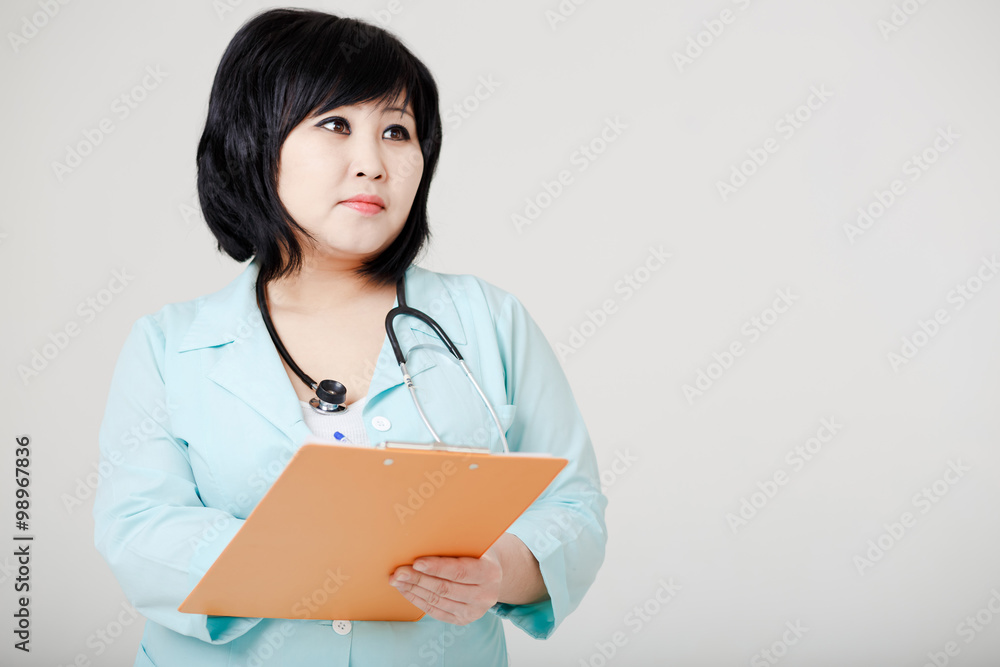 Young female Asian doctor with stethoscope standing still, think Young female Asian doctor with stethoscope standing still, think