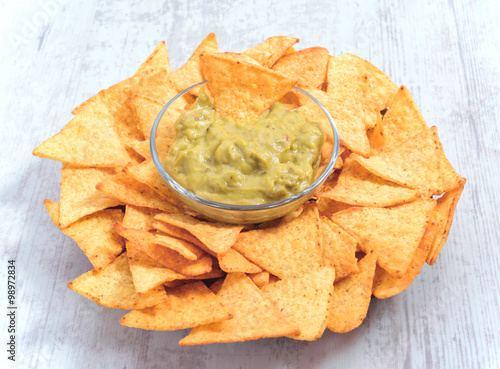 bowl of guacamole sauce surrounded by nachos