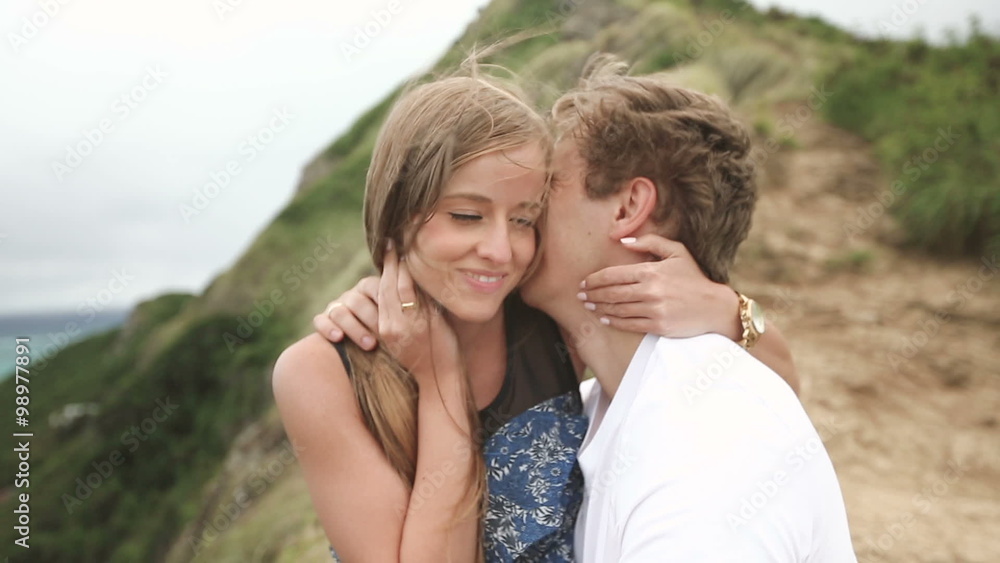 Young couple kissing and enjoying an intimate moment, laughing a lot and woman gently strokes his partner's hair, Oahu, Hawaii. Young couple kissing and enjoying an intimate moment, laughing a lot and woman gently strokes his partner's hair, Oahu, Hawaii.