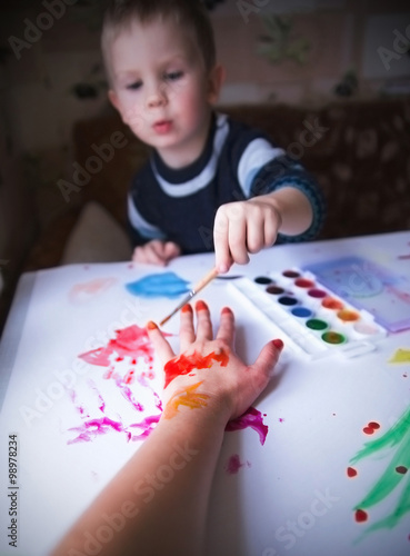 Cute little boy painting with brush