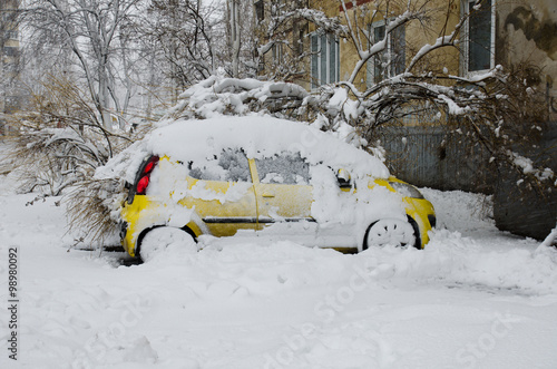 Yellow snow-covered car parked near the house in snowy weather © somemeans