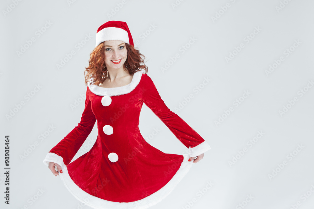 Christmas and New Year Concept and Ideas. Sexy Looking Young Caucasian Red Haired Female in Santa Hat Posing Against White Background Christmas and New Year Concept and Ideas. Sexy Looking Young Caucasian Red Haired Female in Santa Hat Posing Against White Background