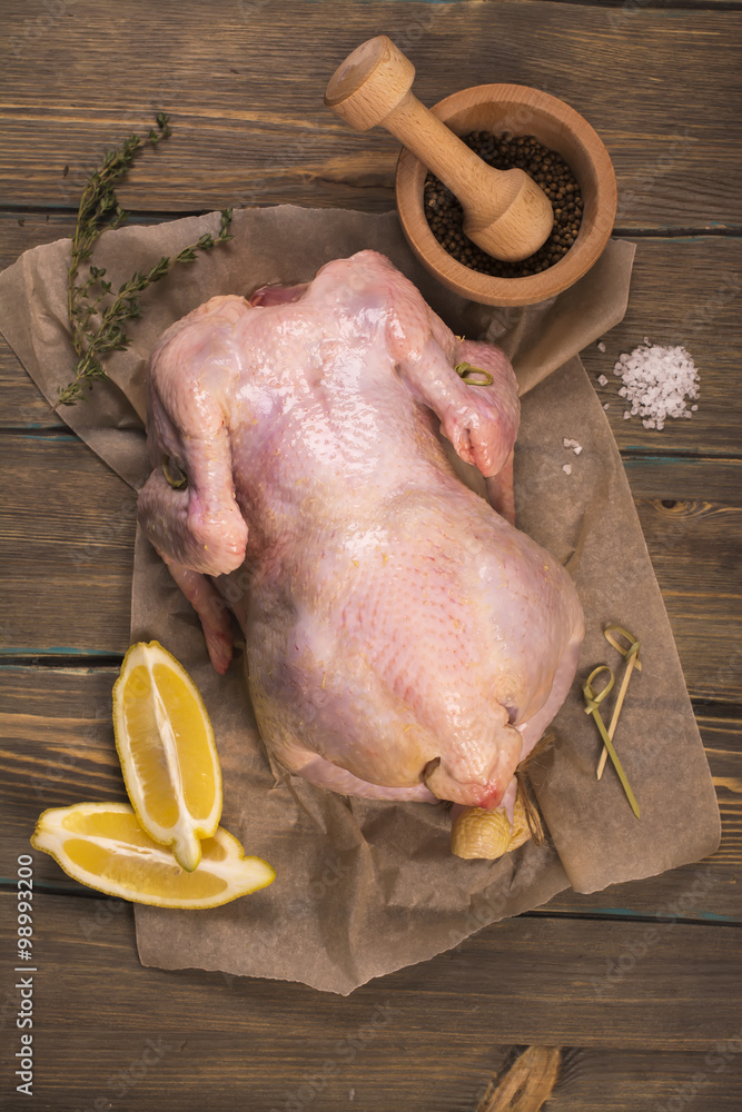 Raw whole chicken ready for baking over wooden table. Top view. Raw whole chicken ready for baking over wooden table. Top view.