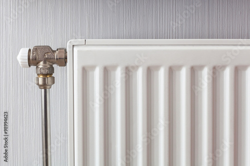 Heating white radiator with adjuster of warming in living room.
